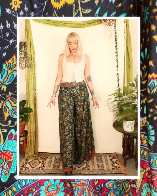 Bohemian silk flared trousers, pull on style with elasticated waist, high waisted with side pockets, funky black and green floral pattern, available in sizes small, medium and large.